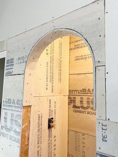 an open wooden door in the side of a building with construction materials around it and under construction signs on the wall