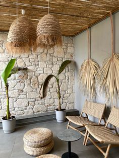 an indoor area with chairs, tables and hanging plants on the wall next to stone walls