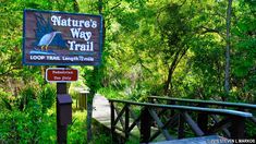 a sign for the nature's way trail in front of some trees and bushes