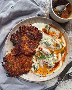 a plate with some food on it next to a bowl of sauce and a spoon