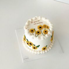 a white cake with sunflowers painted on it