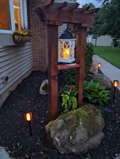 a lantern is lit in the middle of a garden with rocks and plants around it