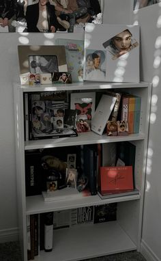 a white book shelf filled with lots of books next to a mirror and pictures on the wall