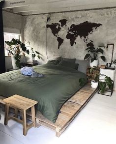 a bed with green sheets and pillows in a room that has a world map on the wall