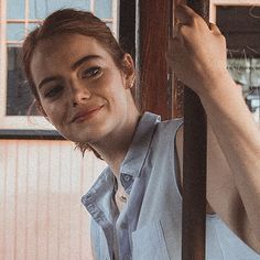 a woman leaning against a pole with her hand on the rail and looking at the camera