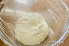 a doughnut in a clear plastic bowl on a wooden table top with the icing removed