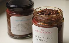 two jars filled with food sitting on top of a white counter next to each other