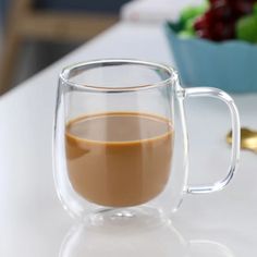 a glass mug with liquid in it sitting on a table