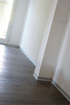 an empty room with wood floors and white walls