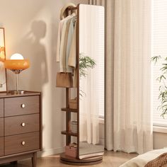 a bedroom scene with focus on the dresser and clothes hanging in front of the mirror