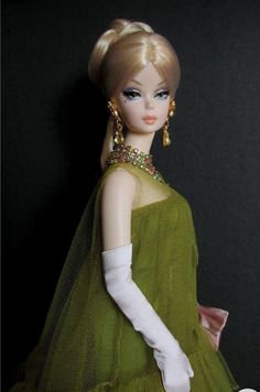 a doll wearing a green dress and white gloves