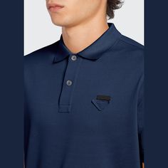 Prada polo in pique knit with tone-on-tone triangle logo on the chest. Approx. 27.5"L from shoulder to hem. Spread collar; two-button placket. Short sleeves. Slim fit. Vented hem. Pullover style. Cotton. Made in Romania. Luxury Blue Collared Polo Shirt, Luxury Navy Polo Shirt, Navy Formal Polo Shirt, Modern Polo Shirt With Polo Collar For Business, Modern Polo Shirt For Business, Luxury Business Polo Collar Tops, Designer Collared Polo Shirt For Formal Occasions, Luxury Business Tops With Polo Collar, Knit Logo