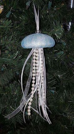 a jellyfish ornament hanging from a christmas tree with beads and pearls on it