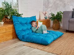 a young boy sitting on a bean bag chair reading a book in the living room