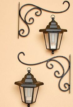 two wall mounted lights are attached to the side of a building with wrought iron work