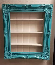 a blue frame with shelves in the middle and an empty shelf below it on top of a wall