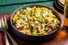 a bowl filled with chicken and vegetables next to silverware