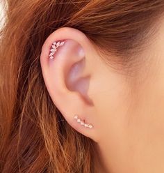 a close up of a person's ear with some piercings on top of it