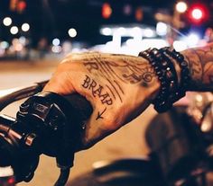 a man with tattoos on his arm holding onto a motorcycle