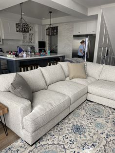 a living room with a large sectional couch in front of an open kitchen and dining area