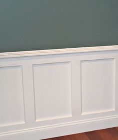 a white headboard against a gray wall in a room with hardwood floors and hard wood flooring