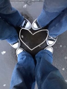 two people standing in front of a heart shaped chalkboard on the ground with their feet crossed