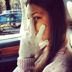 a woman in a car holding her hand up to her face while talking on the phone