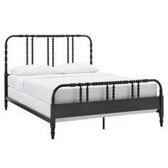 a black metal bed frame with white sheets and pillows on it's headboard