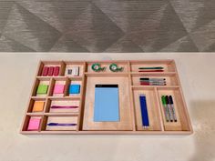 an organized wooden drawer with pens, scissors and other office supplies on it's tray