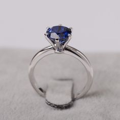 a blue diamond ring sitting on top of a white cloth