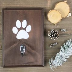 a dog paw print on a wooden plaque surrounded by pine cones