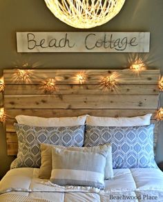 a bed with lights on the headboard above it and a sign that reads beach cottage