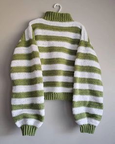 a green and white knitted sweater hanging on a wall with the top half turned down