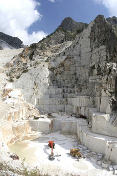 a man standing on top of a snow covered mountain next to a large rock formation