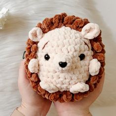 a hand holding a crocheted animal made to look like a lion's head