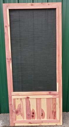 a wooden frame holding a blackboard and some wood pieces in front of a green wall