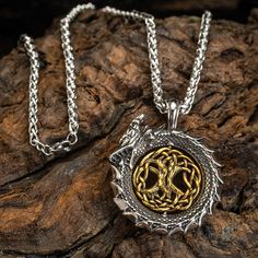 two silver and gold necklaces on top of a wooden log with a tree of life in the center