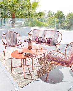 three chairs and a table on a patio with palm trees in the backround