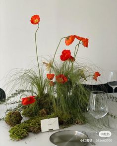 an arrangement of flowers and plants on a table with place cards in front of it