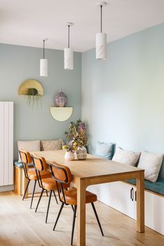 a dining room table with four chairs and a bench in front of the wall,