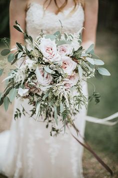 a bride holding a bouquet of flowers and greenery