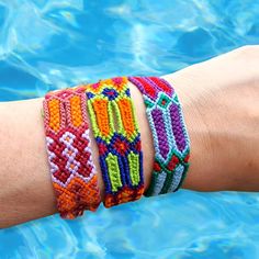 a person's arm with three bracelets on it, in the water and one is wearing a watch