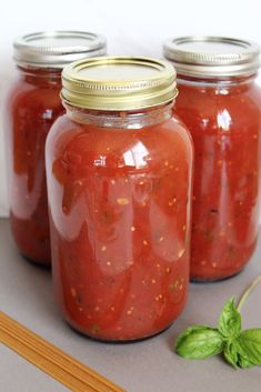 three mason jars filled with tomato sauce and basil