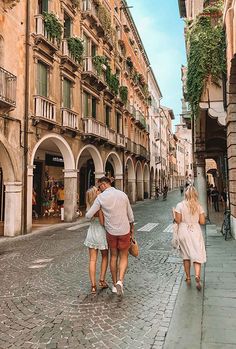 three people walking down the street in an old european city with stone buildings and cobblestone streets