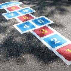 a street sign with numbers and symbols painted on the ground in front of a tree