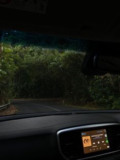 the dashboard of a car with trees and bushes in the background, as seen from inside