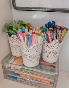 several cups with pens and pencils in them