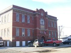 two trucks parked in front of an old brick building with white trim on the windows