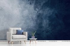 a white chair sitting in front of a wall with blue and gray paint on it