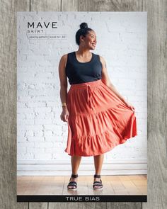 a woman is standing in front of a white brick wall wearing a red skirt and black tank top